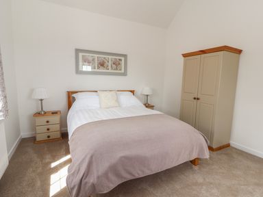 A bedroom with a double bed, two bedside tables with lamps, a wardrobe, and a framed picture above the bed at Delfryn in Llannefydd near Denbigh
