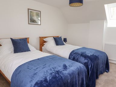 A bedroom with two single beds with blue blankets and pillows and a framed picture on the wall at Delfryn Llannefydd near Denbigh
