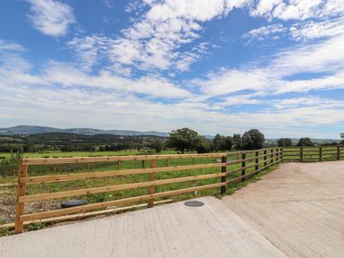 A wooden fence on a concrete surface with green fields and trees in the background at Delfryn Llannefydd near Denbigh