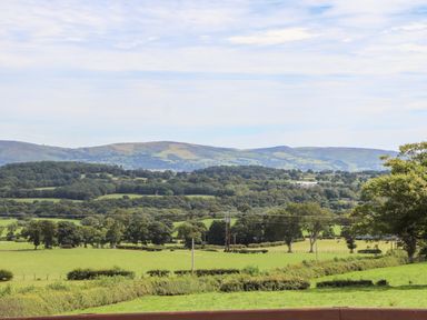 A rural landscape with green fields trees and hills in the distance at Delfryn Llannefydd near Denbigh