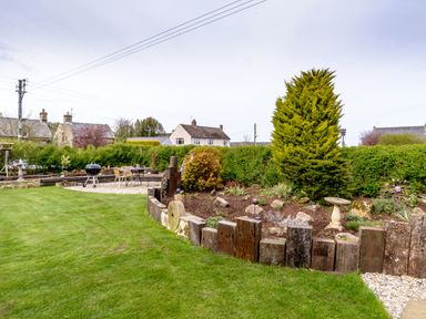 A garden with grass hedge wooden border and outdoor seating with a barbecue at The Old School Room in Longhorsley near Morpeth and Alnwick