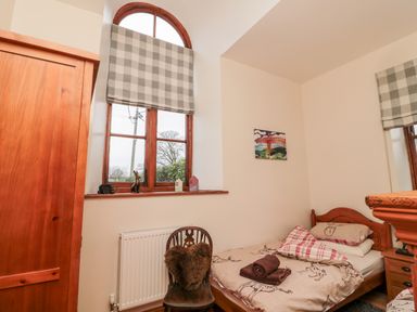 A small bedroom with a single bed next to a window with checkered blinds at The Old School Room in Longhorsley near Morpeth and Alnwick