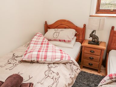 A bedroom with two single wooden beds a bedside table with a lamp and towels at The Old School Room in Longhorsley near Morpeth and Alnwick
