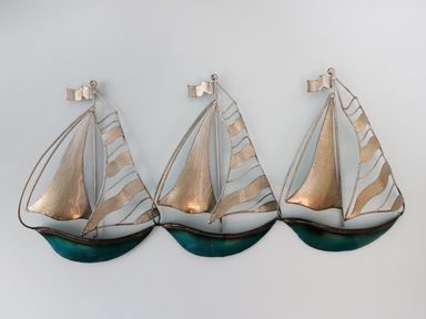 A metal wall decoration of three sailboats with silver sails and blue hulls at Number Fifteen in Withernsea