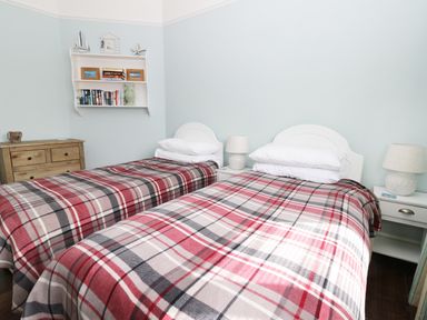 A bedroom with two single beds with plaid blankets and white headboards and bedside tables with lamps at Number Fifteen in Withernsea