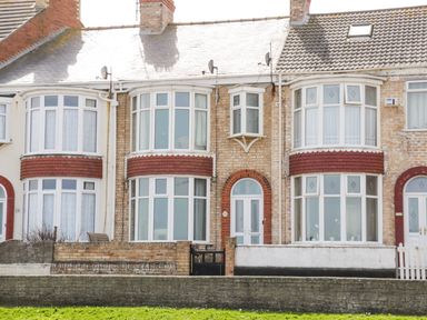 A row of brick and tiled terraced houses with bay windows and small front gardens at Number Fifteen in Withernsea