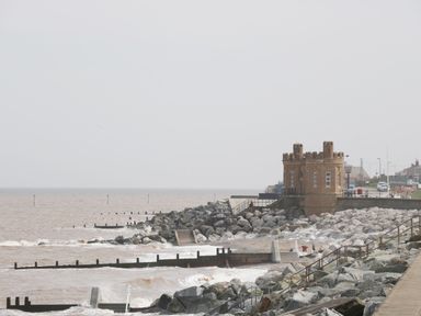 A rocky coastline with a sea defense structure and a castle-like building at Number Fifteen in Withernsea
