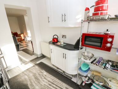 A kitchen with a red microwave on a metal shelf and a kettle on a countertop at Chapel Green Studio in Polgooth near St Austell