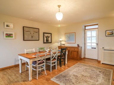 A dining room with a wooden table and mixed color chairs near a wooden sideboard and door at Ballintlea Ballintlea near Dungarvan County Waterford