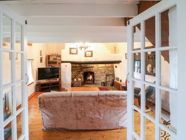 A living room with a sofa facing a fireplace and a television on a stand at Ballintlea in Ballintlea near Dungarvan County Waterford