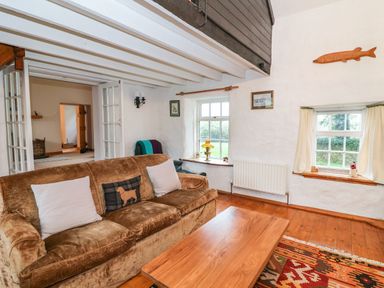 A living room with a brown sofa a wooden coffee table wall decorations and windows at Ballintlea near Dungarvan County Waterford