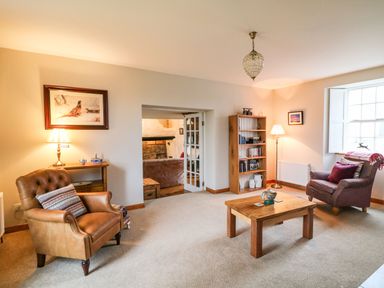 A living room with two armchairs a wooden coffee table a bookshelf and two lamps at Ballintlea Ballintlea near Dungarvan County Waterford