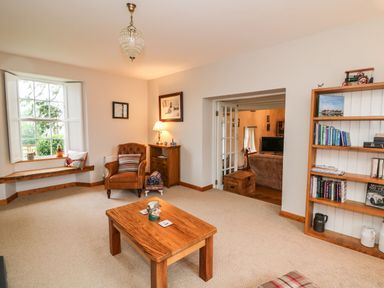 A sitting room with a wooden coffee table armchair bookshelf and a window seat at Ballintlea in Ballintlea near Dungarvan County Waterford