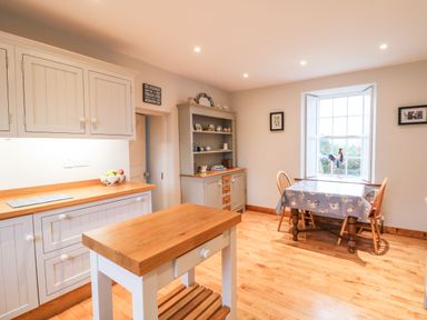 A kitchen with wooden countertops a small island a dining table with chairs and a large window at Ballintlea near Dungarvan County Waterford