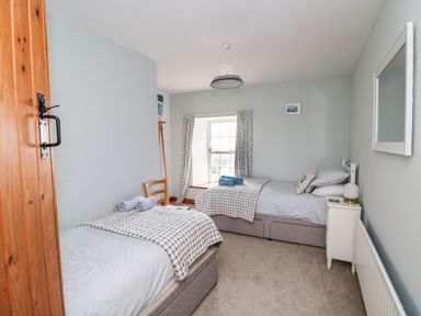 A bedroom with two single beds a wooden chair a window with curtains and a bedside table with a lamp at Ballintlea near Dungarvan County Waterford