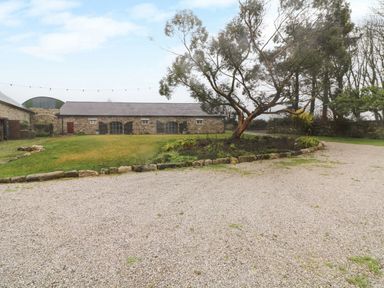 A courtyard with a gravel driveway a tree in a stone-bordered garden and a stone building at Ballintlea near Dungarvan County Waterford