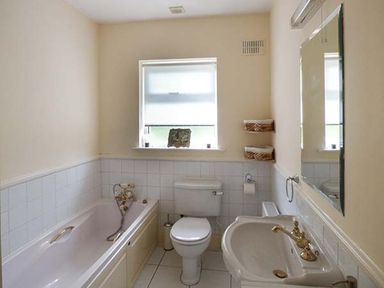 A bathroom with a bathtub toilet and sink under a window at The Sanctuary in Killavullen near Mallow