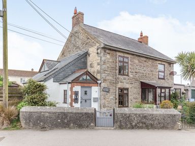 A stone cottage with a gray gate and garden at Victoria Cottage St Newlyn East near Newquay