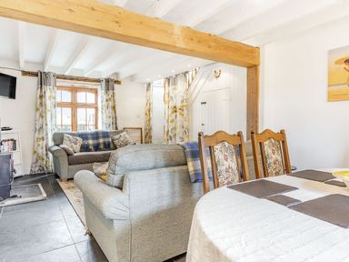 A living room with two sofas a dining table with chairs and a wood beam at Victoria Cottage in St Newlyn East near Newquay