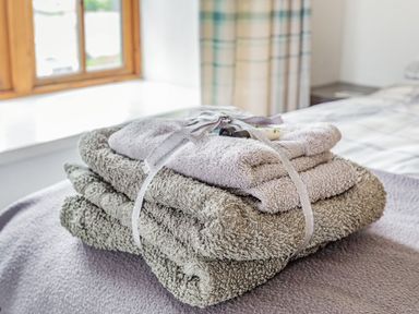 A stack of folded towels tied with a ribbon on a bed in a bedroom at Victoria Cottage in St Newlyn East near Newquay
