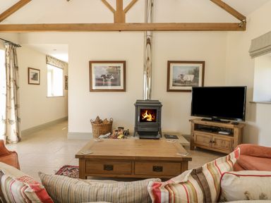 A living room with a wood stove tv and wooden coffee table at Cow Byre in Malton