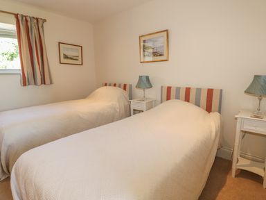 A bedroom with two single beds white bedside tables and lamps at Cow Byre in Malton