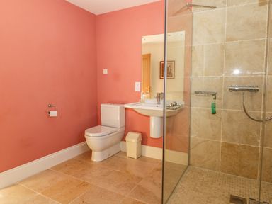 A bathroom with a toilet sink and glass shower at Cow Byre in Malton