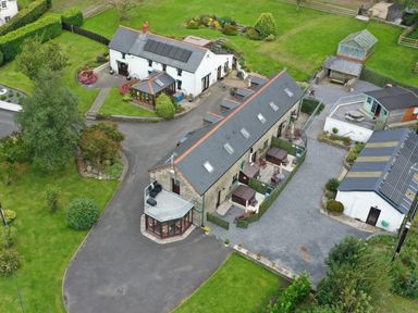 Aerial view of a residential property with stone and white buildings gardens driveways and greenhouses at Oak Cottage Bryngwenith near Newcastle Emlyn