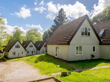 A group of houses with pitched roofs and green lawns under a blue sky at Brookside in Honicombe Manor near Gunnislake