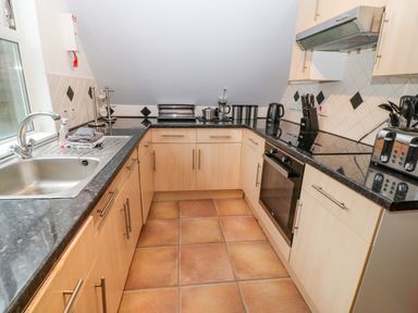 A kitchen with wooden cabinets black countertops a stainless steel sink oven toaster and kettle at Brookside in Honicombe Manor near Gunnislake