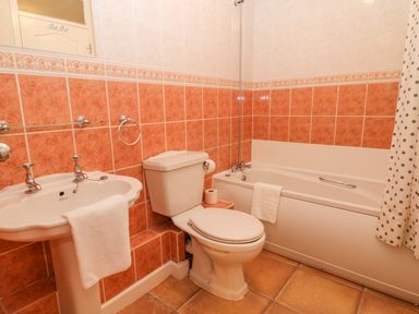 A bathroom with a sink, toilet, bathtub, and polka dot shower curtain at Brookside in Honicombe Manor near Gunnislake