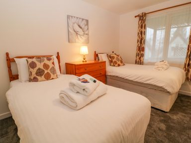 A bedroom with two single beds a wooden chest of drawers and a lamp at Brookside in Honicombe Manor near Gunnislake