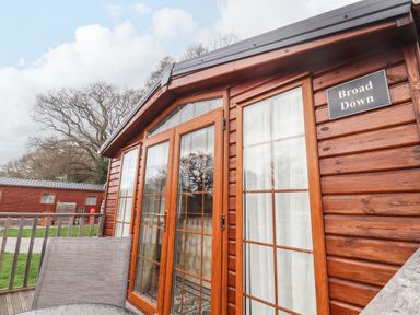 A wooden cabin exterior with glass panel doors and a sign reading Broad Down at Broad Down in Berrow