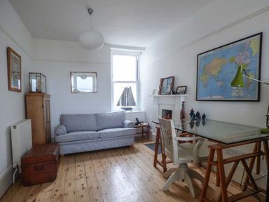 A room with a sofa desk chair and a world map on the wall at Sandy Bank in Rhosneigr