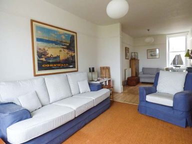 A living room with blue and white sofas a large wall poster and wooden furniture at Sandy Bank in Rhosneigr