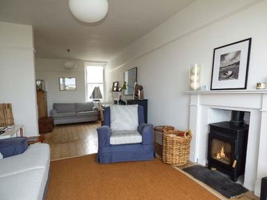 A living room with armchairs a fireplace a basket and a sofa at Sandy Bank in Rhosneigr