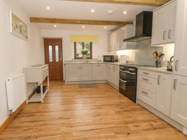 A kitchen with wooden floor cabinets appliances and a wooden door at Caer Moel in Caernarfon