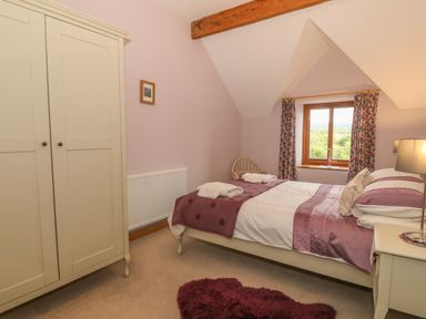 A bedroom with a double bed and wardrobe and window with curtains at Caer Moel in Caernarfon