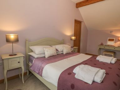 A bedroom with a bed bedside tables lamps and a dressing table with a stool at Caer Moel in Caernarfon