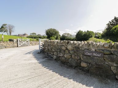 A driveway with stone walls and white gates at Caer Moel in Caernarfon