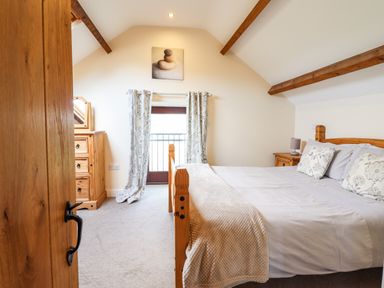 A bedroom with a wooden bed a dresser and a window with curtains at Beudy Bach Barn Llanuwchllyn near Bala