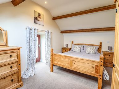 A bedroom with a wooden bed chest of drawers and bedside tables with lamps at Beudy Bach Barn Llanuwchllyn near Bala