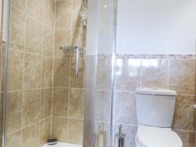 A bathroom with a glass shower enclosure and a toilet at Arfryn in Bethesda