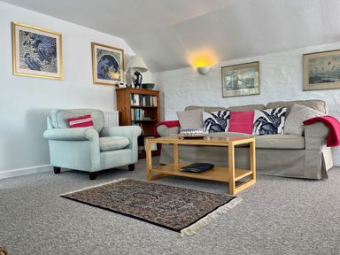 A living room with a sofa armchair coffee table rug and framed pictures on the wall at The Boat House in Golant near Tywardreath