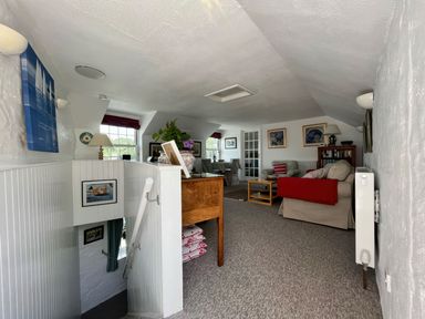 An upstairs living area with sofas coffee tables framed pictures and stairs leading down at The Boat House in Golant near Tywardreath