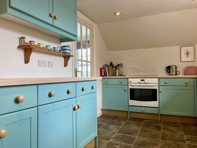 A kitchen with blue cabinets a white oven and utensils on the counter at The Boat House in Golant near Tywardreath