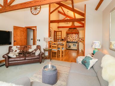 A living room with two sofas a small round table and exposed wooden beams at The Wagon House in Tresmeer near Launceston