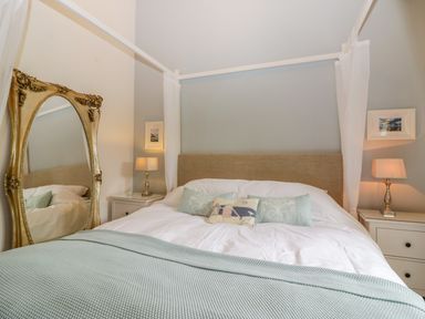 A bedroom with a canopy bed two bedside tables lamps and a large ornate mirror at The Wagon House in Tresmeer near Launceston