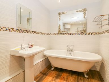 A bathroom with a clawfoot bathtub a pedestal sink two mirrors and a towel rack at The Wagon House in Tresmeer near Launceston