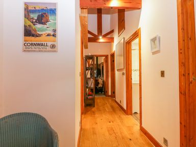 A hallway with wooden floor beams and framed pictures on the walls at The Wagon House in Tresmeer near Launceston